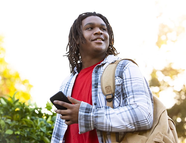 young man with backpack and cell phone outdoors