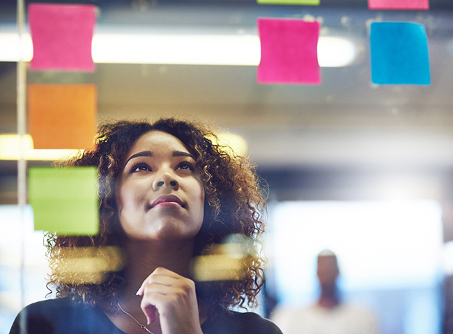 A college entrepreneur looks at her notes pasted on a window.