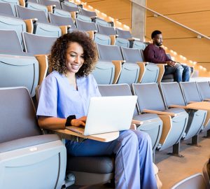 A grad student studying nursing works at her laptop in a lecture hall.