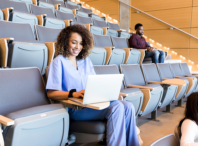 A grad student studying nursing works at her laptop in a lecture hall.