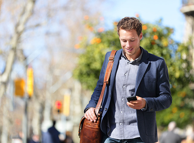 A recent grad walks outside with his phone to help with his job search.