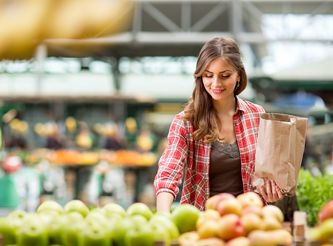 A young woman shops for fruit using her entry level salary 