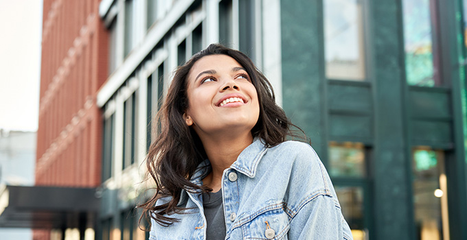 A recent grad smiles and looks up in a city.