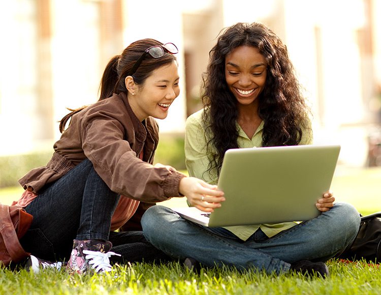 Two young students looking at a laptop